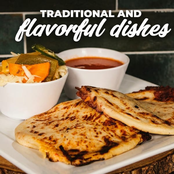 Pupusas with curtido and salsa on a white plate, on a wooden slab.