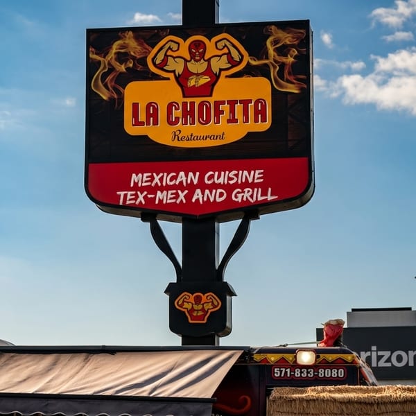 La Chofita Restaurant sign, featuring a luchador and flames, advertising Mexican, Tex-Mex, and Grill cuisine.