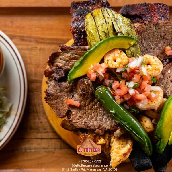El Tolteca's sizzling platter of grilled meats, shrimp, avocado, and peppers, with a side of rice and beans.